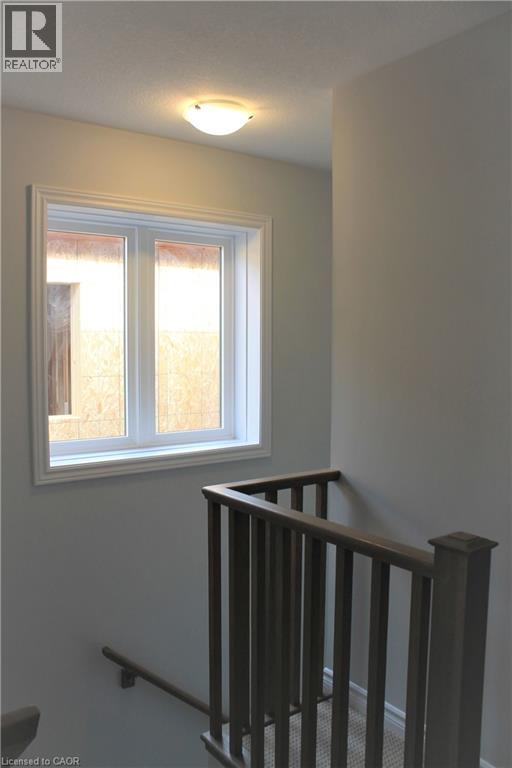 Stairwell featuring light gray walls, white trim, a double window, a semi-flush mount ceiling light, and a wood-finish handrail with balusters - 124 Compass Trail Unit# 14, Cambridge, ON