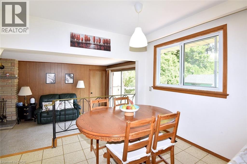 Dining area with a drop pendant light fixture and a large window overlooking lush greenery - 372 Fennell Avenue W, Hamilton, ON