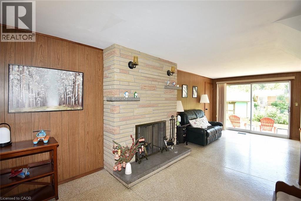 Stone fireplace with a hearth, wood paneling, and sliding glass doors to the exterior - 372 Fennell Avenue W, Hamilton, ON