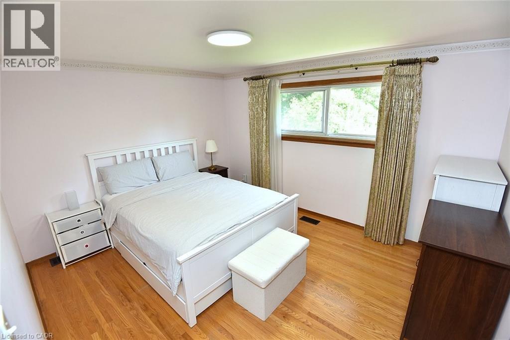 Hardwood flooring throughout featuring a window with natural wood trim, crown molding, and a flush mount ceiling light - 372 Fennell Avenue W, Hamilton, ON