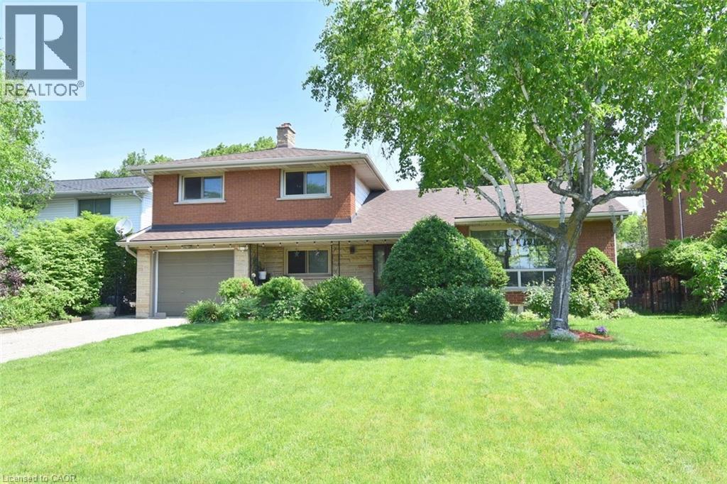 Split-level residence featuring a brick facade, integrated garage, and a lush front lawn - 372 Fennell Avenue W, Hamilton, ON