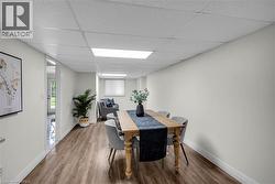 Spacious room featuring wood-finish flooring, crisp white walls, and a dropped ceiling with integrated lighting -