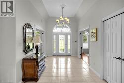 Grand entry foyer featuring tile flooring, vaulted ceiling, and a prominent chandelier -
