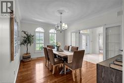 Dining area featuring wood-finish flooring, three arched windows with plantation shutters, crown molding, and a decorative ceiling medallion with a chandelier -