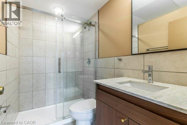 Full bath featuring vanity, tile walls, and a stall shower - 580 Coldstream Drive Unit# 307, Waterloo, ON
