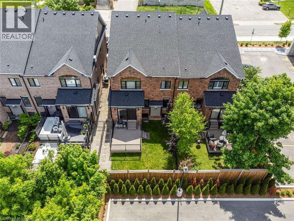 Red brick townhome featuring a private backyard with a deck and established trees - 12 George Street, Waterloo, ON