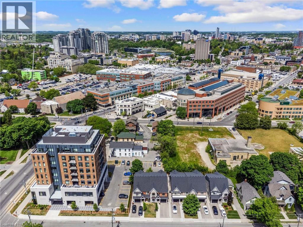Modern mixed-use urban development featuring a contemporary high-rise building with balconies, adjacent to a row of townhouses with private driveways - 12 George Street, Waterloo, ON