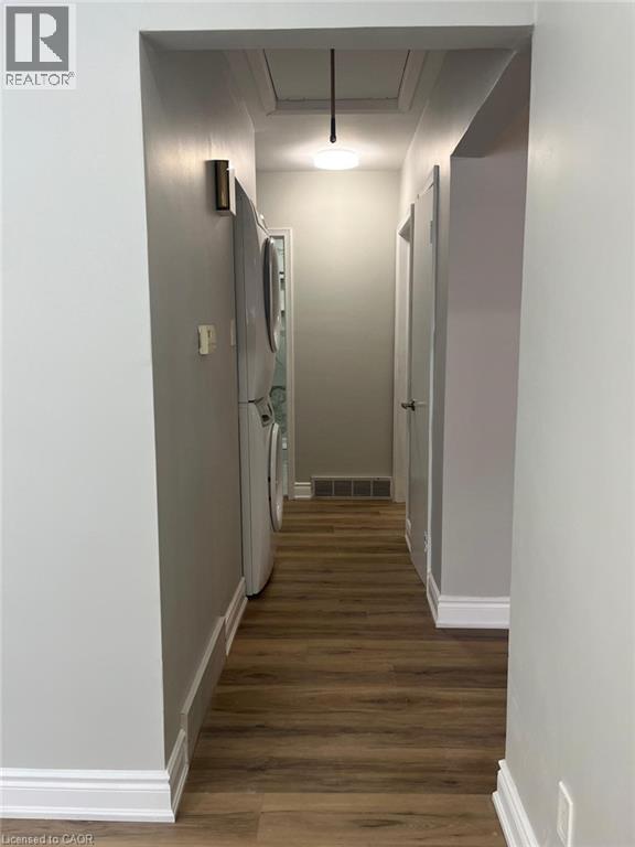 Hallway featuring wood-finish flooring, white baseboards, and light gray walls - 102 Massey Avenue, Kitchener, ON