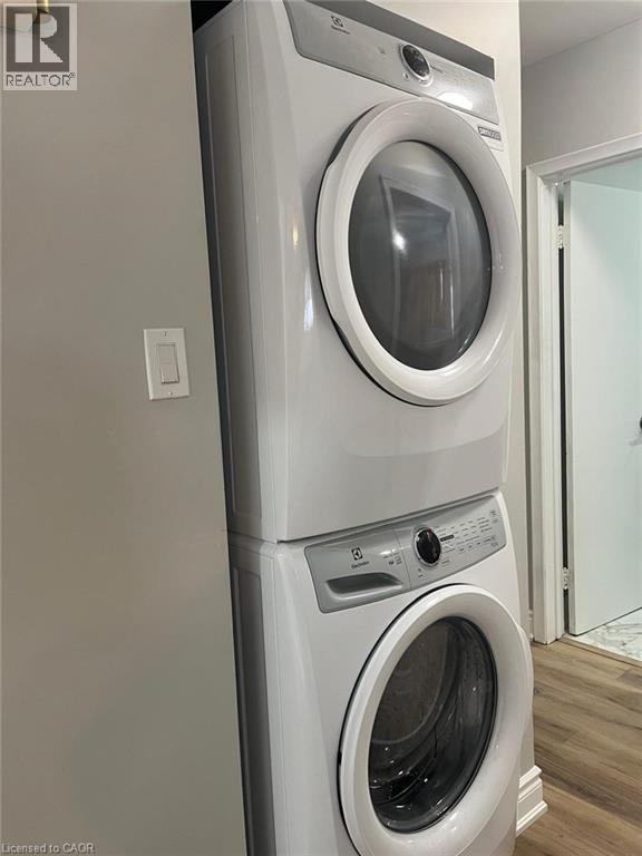 Space-saving stacked washer and dryer unit, featuring a white finish with grey control panels and front-loading doors - 102 Massey Avenue, Kitchener, ON