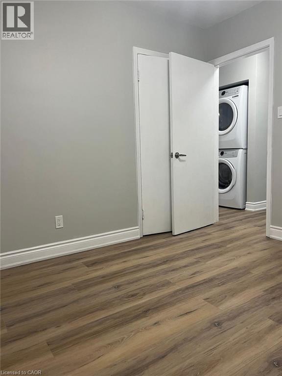 Dedicated laundry closet featuring a stacked white washer and dryer unit - 102 Massey Avenue, Kitchener, ON