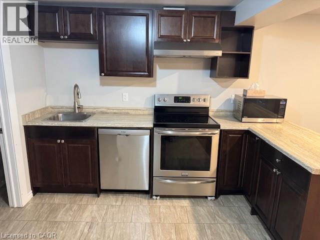 Compact kitchen featuring wood-finish cabinetry, light-toned countertops, and stainless steel appliances - 113 Cornerbrook Crescent Unit# 2, Waterloo, ON