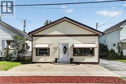 Single-story residence featuring light-colored siding, a dark brown trim, and a gabled roof -
