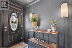 Entryway featuring a paneled door with an oval leaded glass insert, dark wall paint, and crown molding -