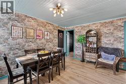 Dining area featuring brick-patterned walls and wood-finish flooring -