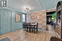 Dining area with wood-finish flooring and a distinctive brick-texture accent wall -