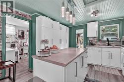 Kitchen featuring white cabinetry, a central island with a solid surface countertop, and wood-finish flooring -