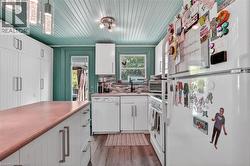 Kitchen featuring a wood-finish flooring, white cabinetry, and a teal beadboard ceiling -