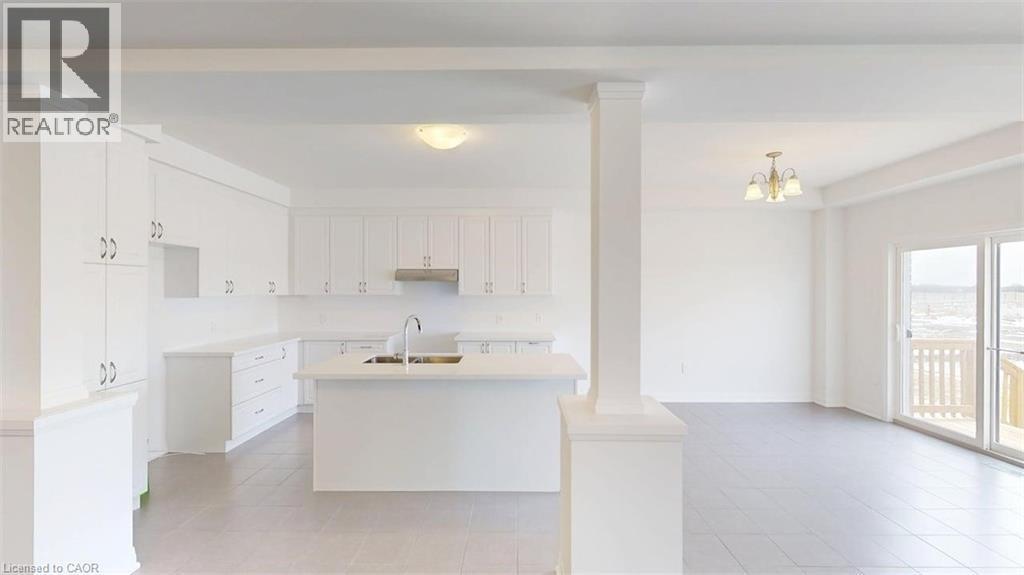 Open-concept kitchen and living area featuring white cabinetry, a center island with a sink, stainless steel range hood, and light-toned tile flooring - 287 Rockledge Drive, Hamilton, ON