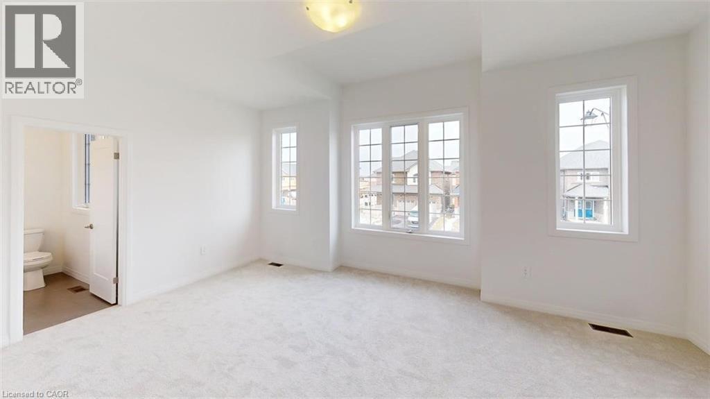 Spacious room featuring light-colored carpeting, multiple large windows with grid patterns, and a ceiling-mounted light fixture - 287 Rockledge Drive, Hamilton, ON