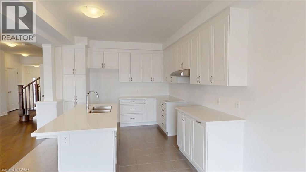Modern kitchen featuring white shaker cabinetry, an integrated island with dual sinks, and light-toned countertops - 287 Rockledge Drive, Hamilton, ON