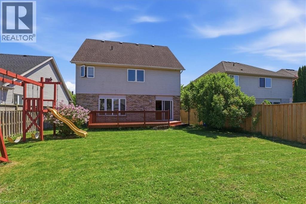 Expansive backyard featuring a manicured lawn, a full-width deck, and a wood privacy fence - 43 Decaro Crescent, Cambridge, ON