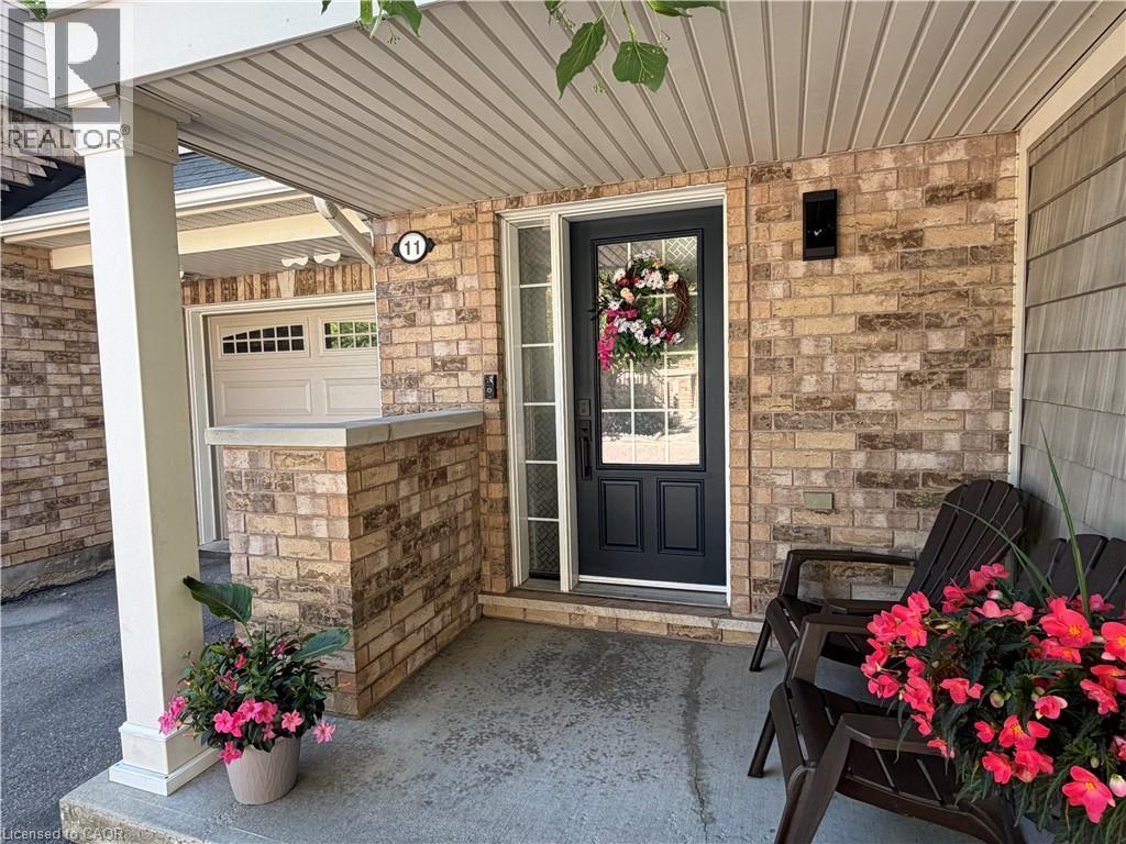 Covered entryway with brick facade, a black front door featuring a glass insert, and a white paneled ceiling - 7 Sirente Drive Unit# 11, Hamilton, ON - Outdoor With Exterior