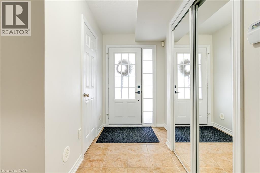 Foyer with tan tile flooring, white baseboards, and a white paneled door - 7 Sirente Drive Unit# 11, Hamilton, ON - Indoor Photo Showing Other Room