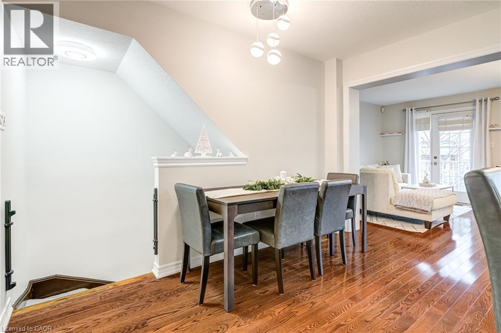 Dining area featuring wood-finish flooring, a contemporary chandelier, and a half-wall partition - 7 Sirente Drive Unit# 11, Hamilton, ON - Indoor Photo Showing Dining Room