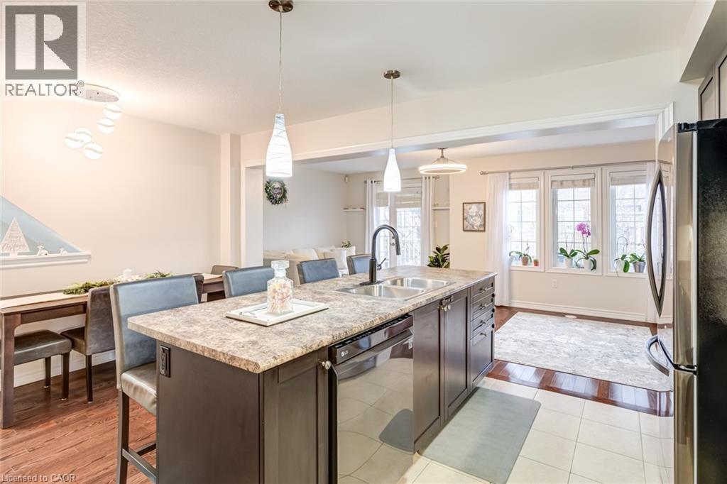 Kitchen island with a double basin sink and a high-arc faucet, featuring a speckled countertop and dark wood-finish cabinetry - 7 Sirente Drive Unit# 11, Hamilton, ON - Indoor Photo Showing Kitchen With Double Sink With Upgraded Kitchen