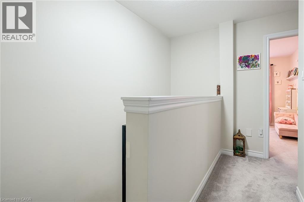 Upper-level hallway with light-toned walls, neutral carpeting, and a white balustrade with decorative molding - 7 Sirente Drive Unit# 11, Hamilton, ON - Indoor Photo Showing Other Room