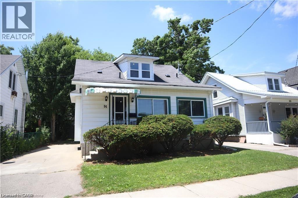 Front exterior showcasing a white siding facade with dark trim accents, a dormer window, and a prominent front entrance with an awning - 94 Brook Street, Simcoe, ON - Outdoor With Facade
