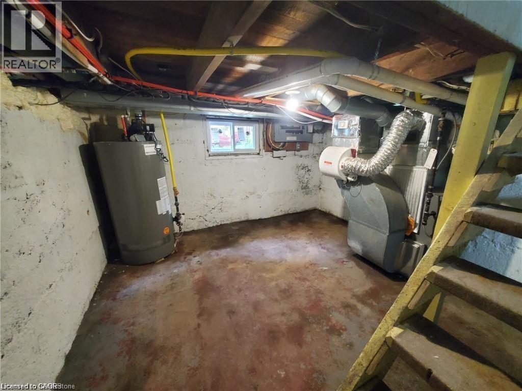Basement utility area featuring a hot water heater, forced air furnace with ductwork, and exposed ceiling joists with visible wiring and plumbing - 94 Brook Street, Simcoe, ON - Indoor Photo Showing Basement