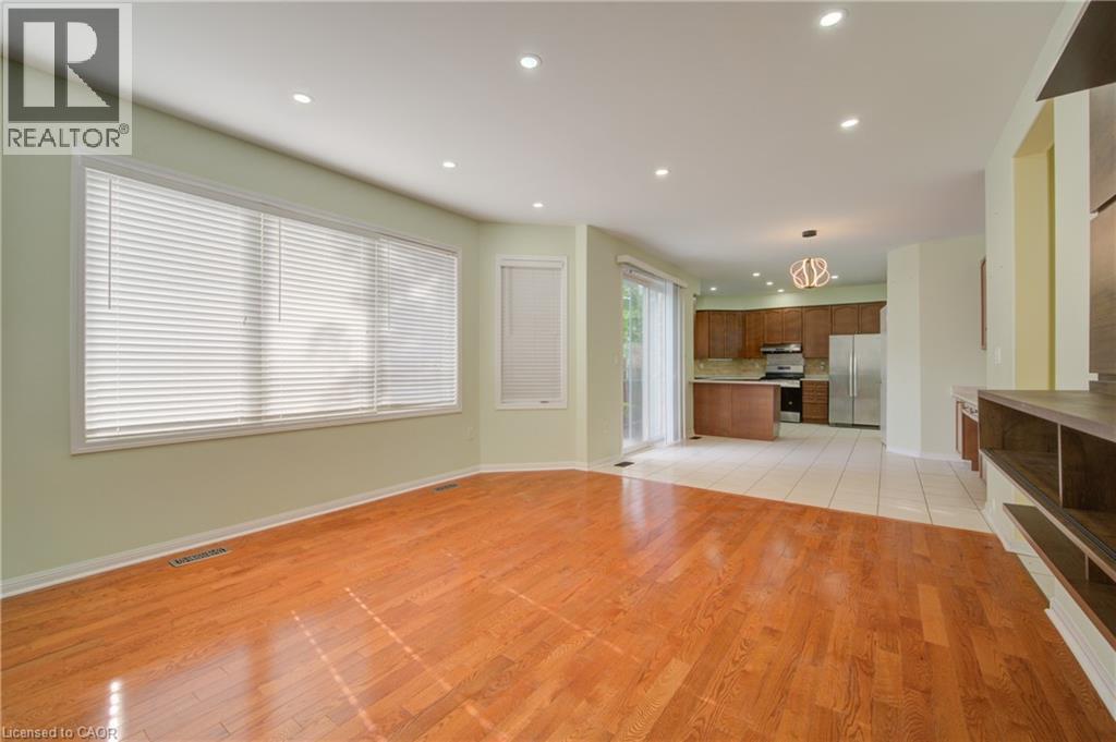 Expansive living area featuring wood-finish flooring, recessed lighting, and large windows - 180 Arthur Fach Drive, Cambridge, ON
