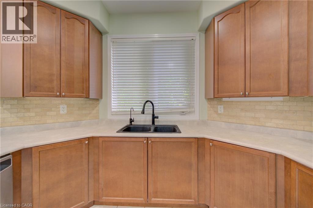 Kitchen featuring wood cabinetry, light-toned countertops, and a subway tile backsplash - 180 Arthur Fach Drive, Cambridge, ON