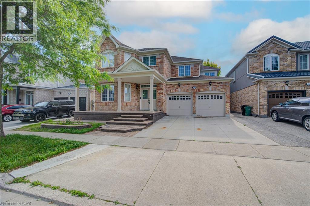Brick facade residence featuring a covered porch with white columns, a double garage, and a concrete driveway - 180 Arthur Fach Drive, Cambridge, ON