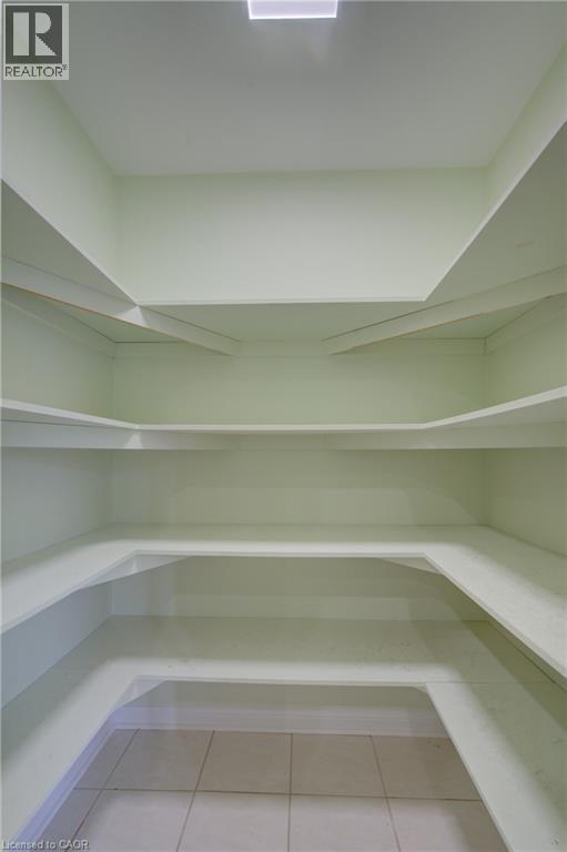 Walk-in pantry featuring expansive shelving, light green wall paint, overhead recessed lighting, and square tile flooring - 180 Arthur Fach Drive, Cambridge, ON