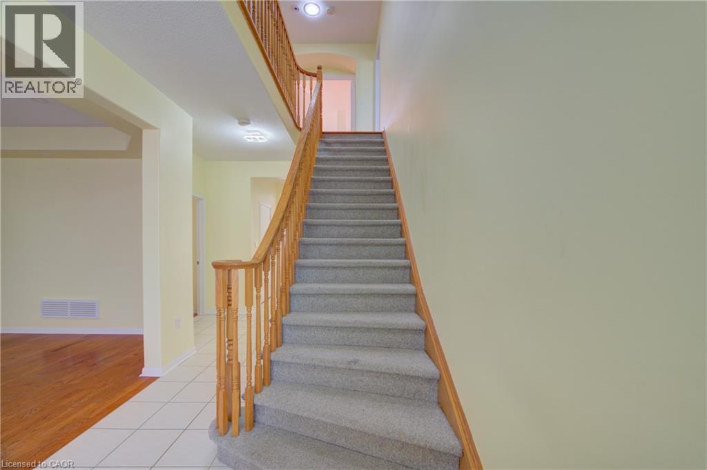 Carpeted staircase featuring a light wood-finish railing and balusters - 180 Arthur Fach Drive, Cambridge, ON