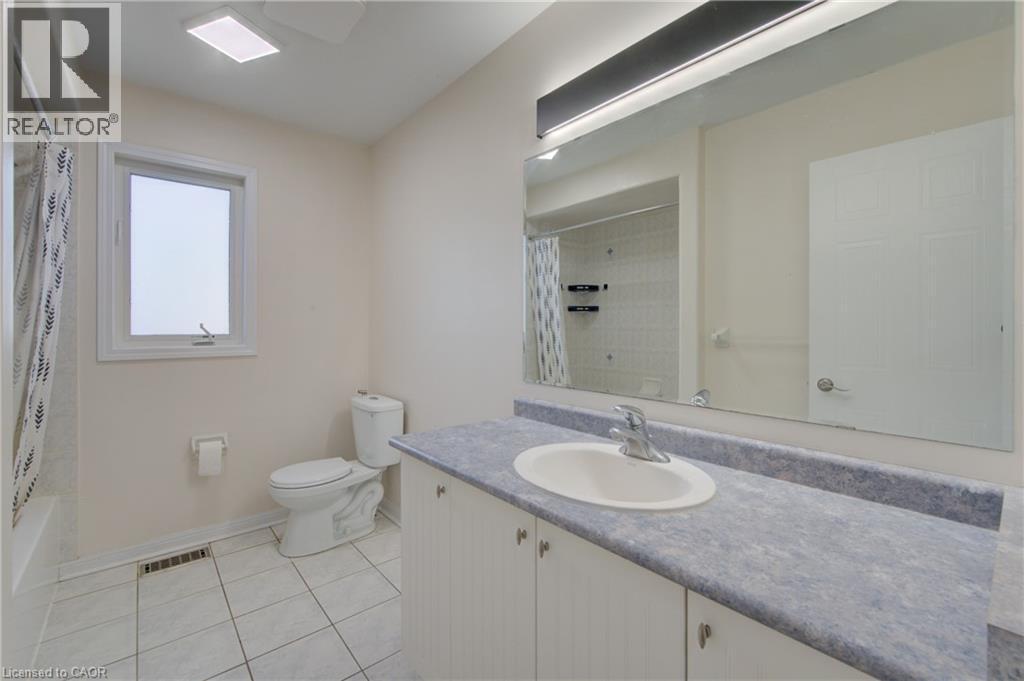 Full bathroom featuring a white vanity with a blue-grey countertop, an integrated sink, and a large wall-mounted mirror - 180 Arthur Fach Drive, Cambridge, ON