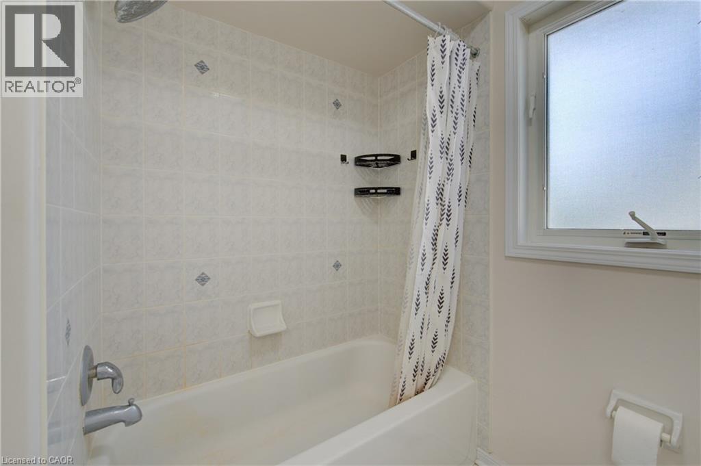 Bathtub with white tile surround featuring decorative accents - 180 Arthur Fach Drive, Cambridge, ON