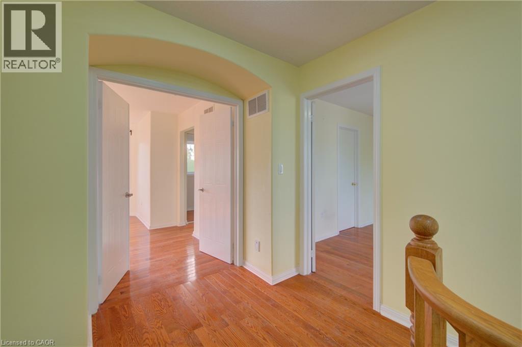 Hallway featuring hardwood flooring, light-toned walls, white trim, and an arched doorway - 180 Arthur Fach Drive, Cambridge, ON
