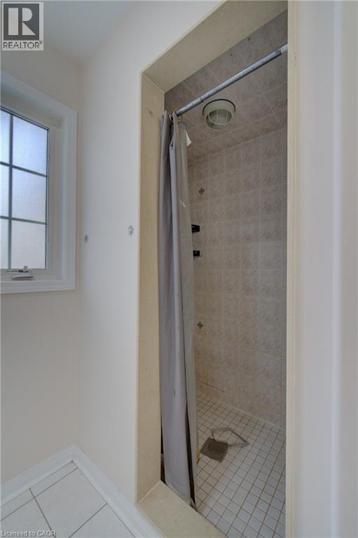 Tiled shower stall with a neutral-toned shower curtain and ceiling-mounted light fixture - 180 Arthur Fach Drive, Cambridge, ON
