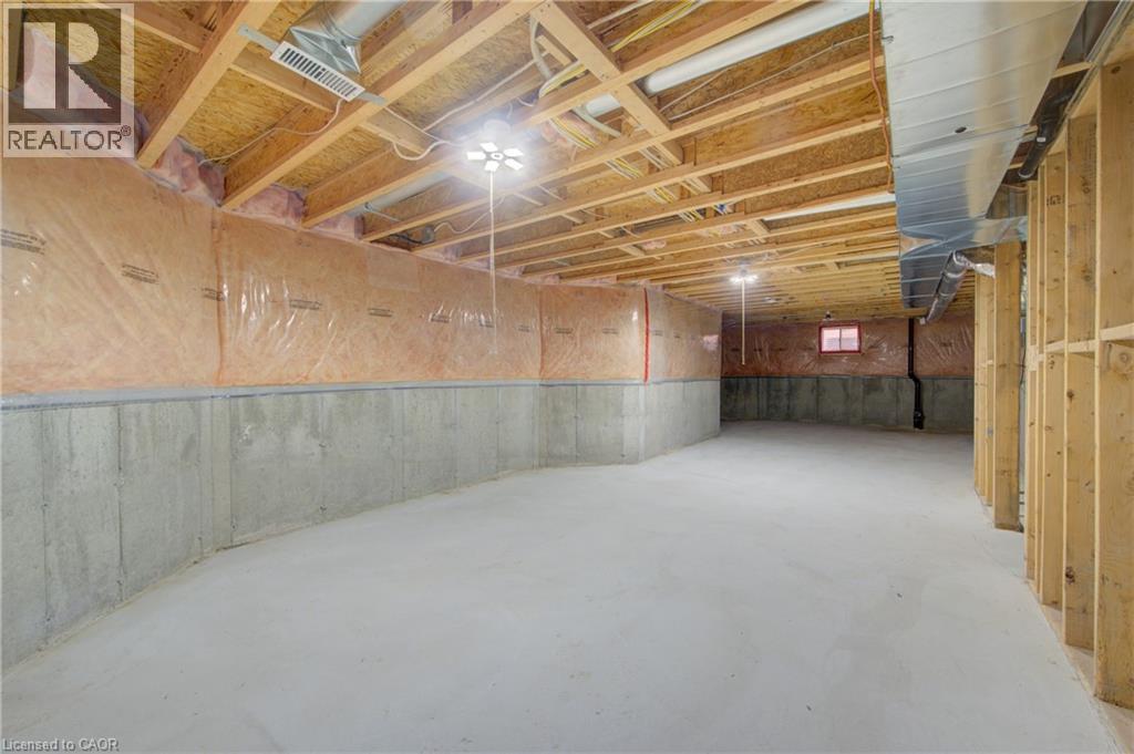 Spacious unfinished basement with concrete flooring and exposed wood ceiling joists - 180 Arthur Fach Drive, Cambridge, ON