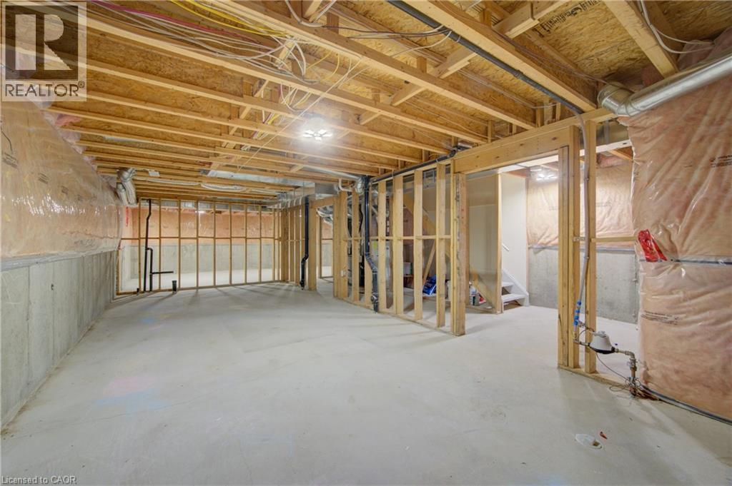 Unfinished basement presenting framed walls, exposed ceiling joists, concrete flooring, and visible utility lines - 180 Arthur Fach Drive, Cambridge, ON