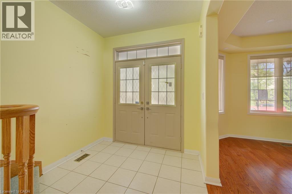 Entry foyer featuring double doors with decorative glass panels and an overhead transom window - 180 Arthur Fach Drive, Cambridge, ON