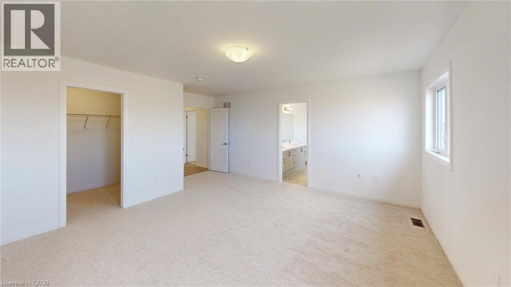 Carpeted room featuring a ceiling-mounted light fixture, white walls, and a window providing natural illumination - 200 Cittadella Boulevard, Hamilton, ON