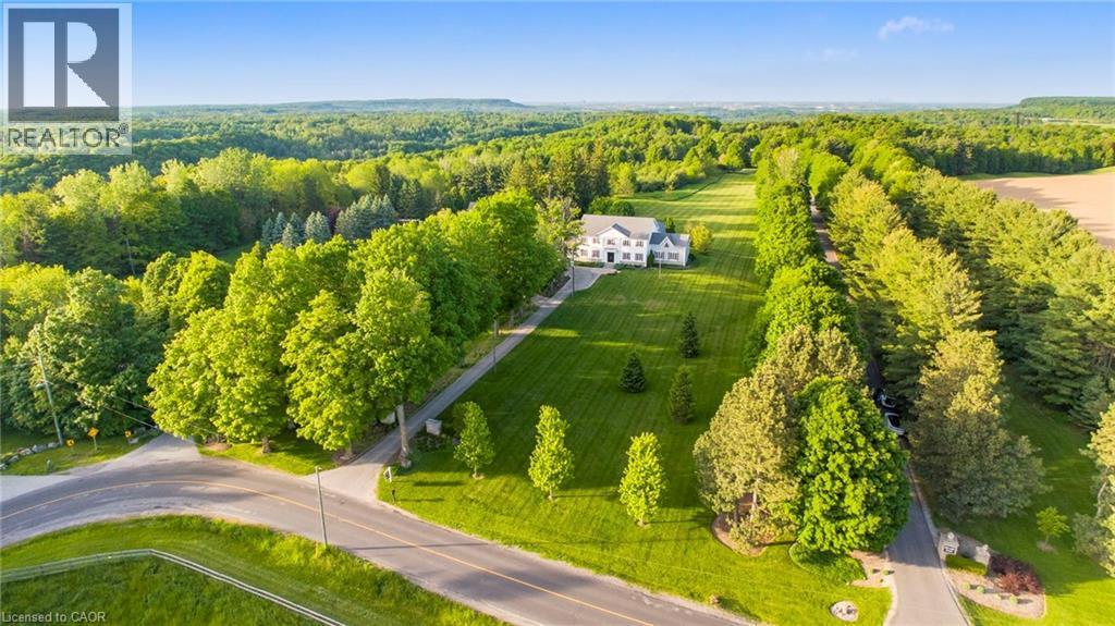 Expansive property featuring a white two-story residence, a long paved driveway, and mature landscaping - 6195 Milburough Line, Burlington, ON - Outdoor With View