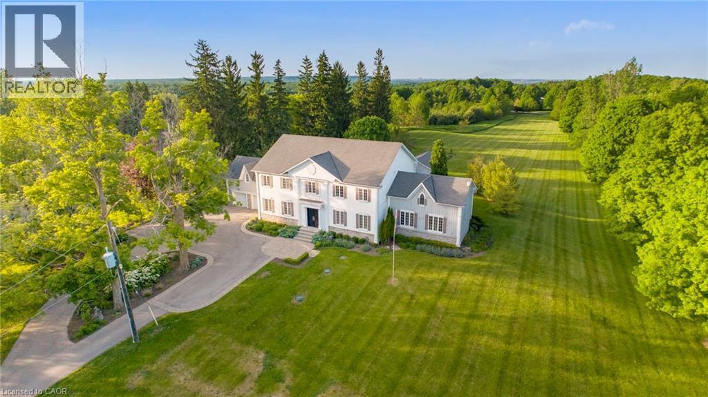 Expansive property featuring a large residence with light-colored siding and a dark roof - 6195 Milburough Line, Burlington, ON - Outdoor With View
