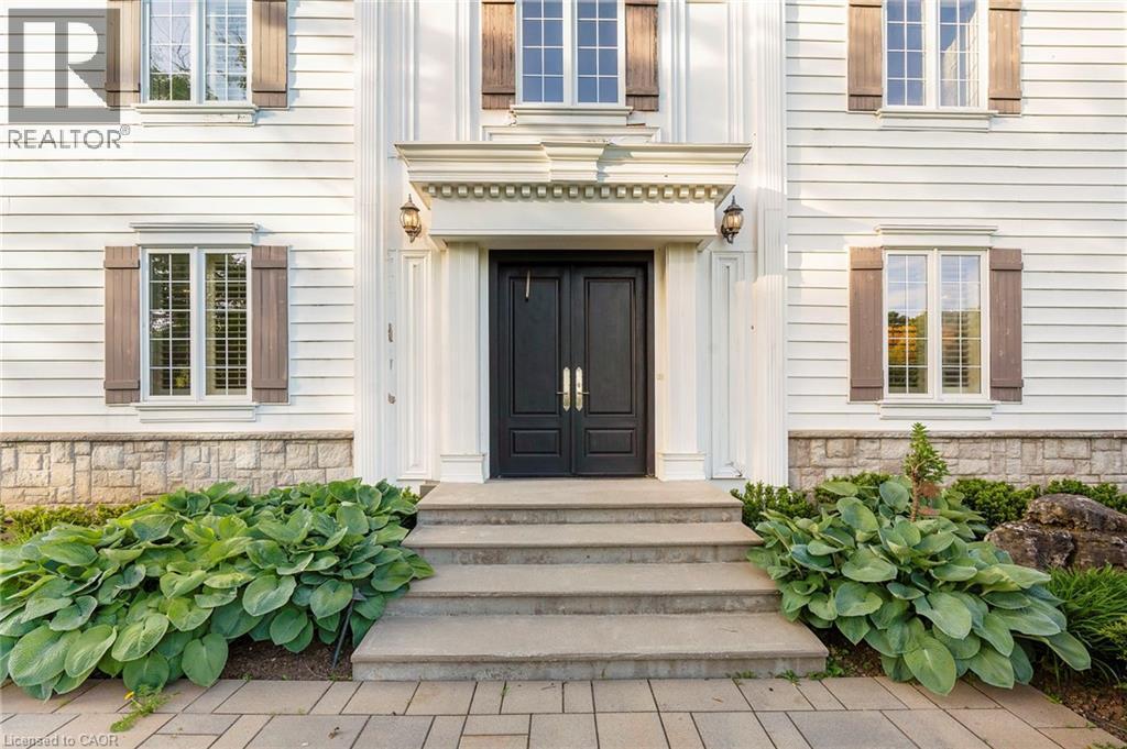White clapboard exterior featuring a double entry door, decorative door surround, wall sconces, and functional shutters - 6195 Milburough Line, Burlington, ON - Outdoor