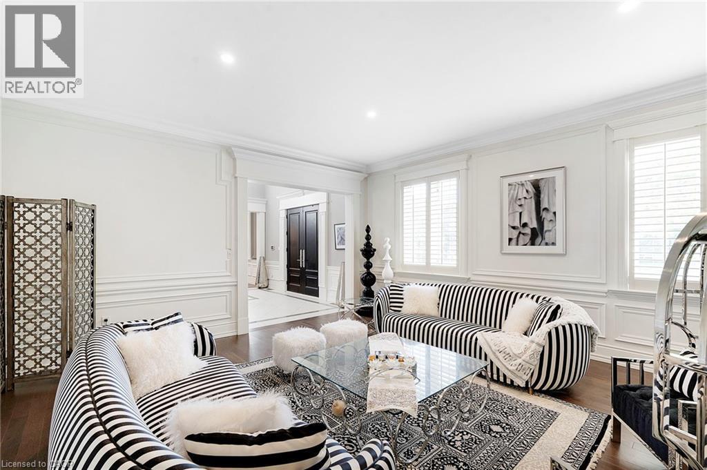 Spacious living area featuring wood-finish flooring, white paneling, and crown molding - 6195 Milburough Line, Burlington, ON - Indoor