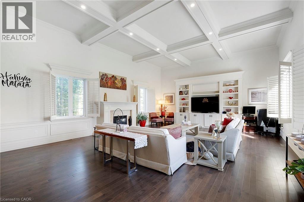Living area featuring coffered ceilings with recessed lighting, wood-finish flooring, a fireplace with a white mantel, and built-in cabinetry - 6195 Milburough Line, Burlington, ON - Indoor Photo Showing Living Room With Fireplace